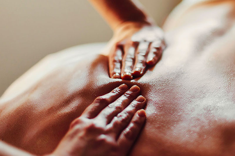 RMT's massaging hands firmly pressing persons back. RMT Massage at Ritual Nordic Spa in Downtown Victoria, BC